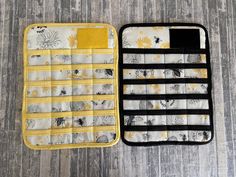 two oven mitts sitting next to each other on a wooden floor with yellow and white designs