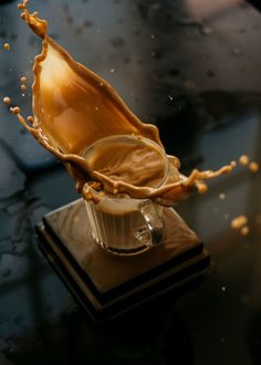 a liquid splashing out of a cup on top of a table