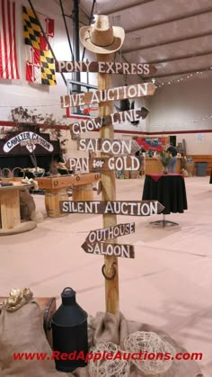 a wooden pole with several signs on it in the middle of a room filled with tables and chairs