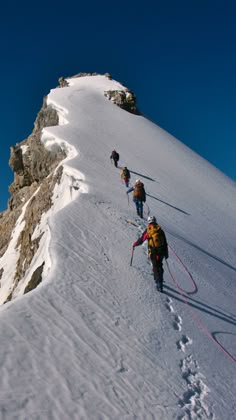 several people hiking up the side of a snow covered mountain