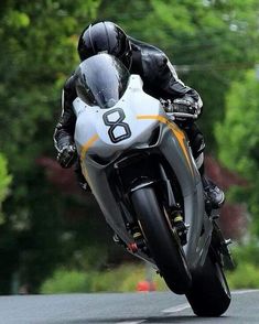 a man riding on the back of a motorcycle down a curvy road with trees in the background