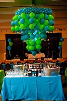 a blue table topped with lots of green balloons and bottles filled with wine on top of it