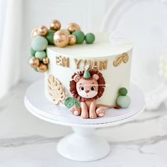 a white cake with a lion on top and gold decorations around the edges, sitting on a pedestal