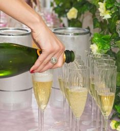 a woman is pouring champagne into wine glasses