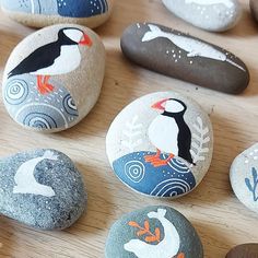 several painted rocks with birds on them sitting on a table next to other rocks and stones