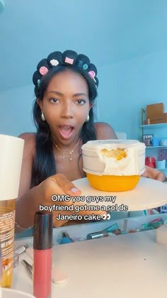 a woman sitting at a table with a bowl of food in front of her face