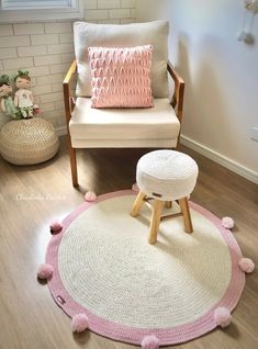 a pink and white rug with pom - poms on the floor next to a chair