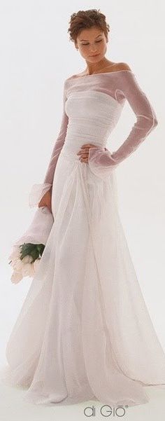 a woman in a white wedding dress holding a bouquet and posing for the camera with her hands on her hips