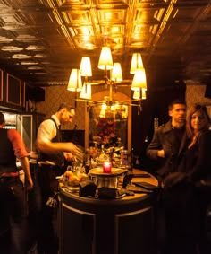 a group of people standing around a table in a room with lights on the ceiling