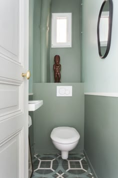 a white toilet sitting inside of a bathroom next to a sink under a mirror on the wall