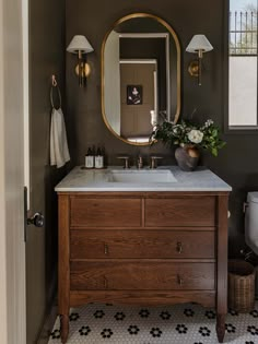 a bathroom with a sink, mirror and lights on the wall next to a toilet