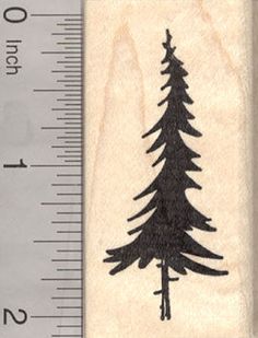 a rubber stamp with a pine tree on it and measuring tape in front of it