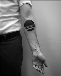 a black and white photo of a man's arm with a circle tattoo on it