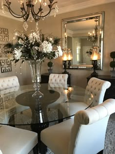 a dining room table with white chairs and a chandelier