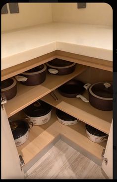 an open cabinet with pots and pans on the bottom shelf in front of it