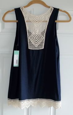 a black top with white crochet on the front and back, hanging from a hanger