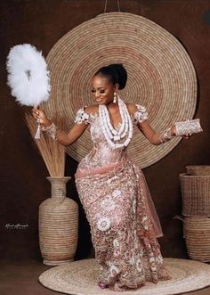 a woman in a pink and white dress holding feathers