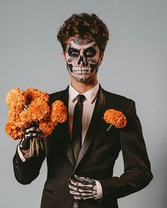 a man in a suit and skeleton makeup holding flowers