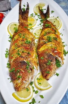 baked whole yellowtail snapper on a white plate with lemons and parsley