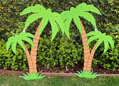 two fake palm trees in front of a hedge