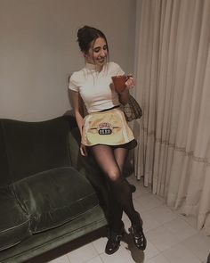 a woman sitting on top of a green couch holding a cup