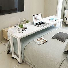 a laptop computer sitting on top of a white desk next to a bed in a bedroom