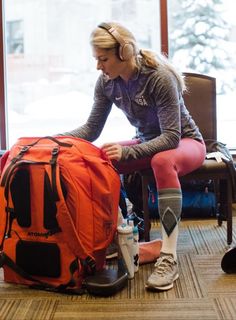 a woman sitting on top of a chair next to an orange backpack