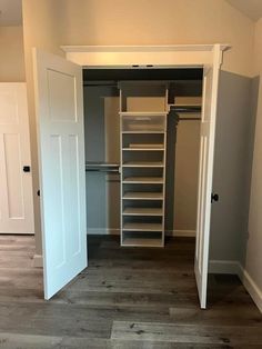 an empty walk in closet with white doors and shelves on the wall next to it