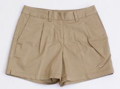 a pair of tan shorts with white nike logo on the front and side pockets, sitting against a white background