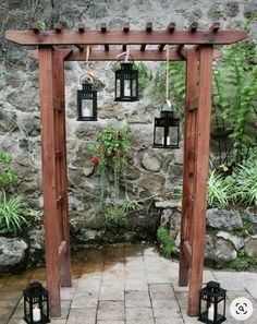 an outdoor wedding ceremony with lanterns hanging from the pergolated arbor and stone walls