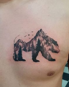 a bear tattoo on the chest with mountains and birds flying around it's neck