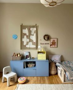 a child's bedroom with a blue dresser and white rug on the wooden floor