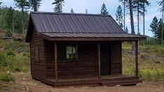 a small wooden cabin in the woods with a metal roof and door on it's side