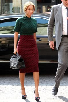 a woman in a green dress is walking next to a man wearing a suit and tie