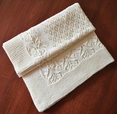 two white knitted napkins sitting on top of a wooden table