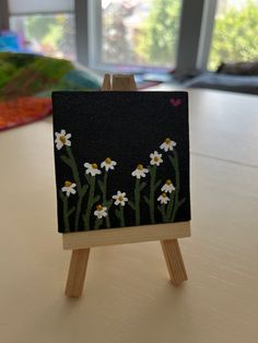 an easel with a painting on it sitting on a table