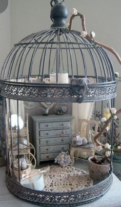 a bird cage sitting on top of a table next to a dresser and chest with drawers