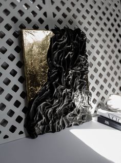 a black and gold piece of art sitting on top of a white table next to a book