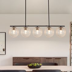 a dining room table with four lights hanging over it