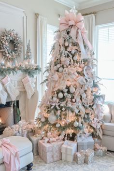 a decorated christmas tree in a living room with presents on the floor and pink bows