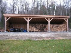 a large pile of wood sitting in the middle of a yard next to a building