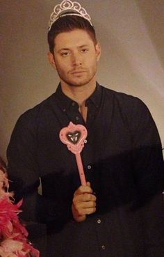 a man wearing a tiara and holding a pink heart shaped key in his hand