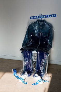 two blue jackets and one white snowboard are on the floor in front of a wall