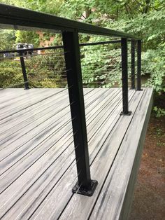 a wooden deck with metal railings and trees in the backgroung area