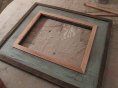 a wooden frame sitting on top of a table next to a paint can and brush