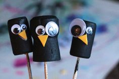 three little black birds with googly eyes on top of toothpicks that are sticking out of sticks