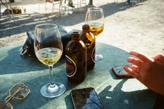 a table with two bottles of wine and glasses on it, next to a cell phone