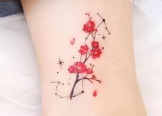 a woman's tattoo with red flowers on the side of her leg and stars in the background