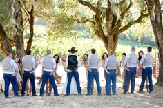 a group of people standing next to each other in front of some trees and bushes