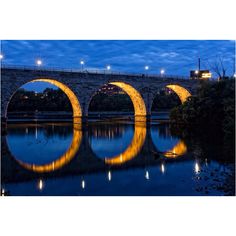 a bridge that is over some water with lights on at the top and below it